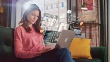 Woman using a laptop with digital interface icons floating around, representing innovative strategies to improve sales in banking.